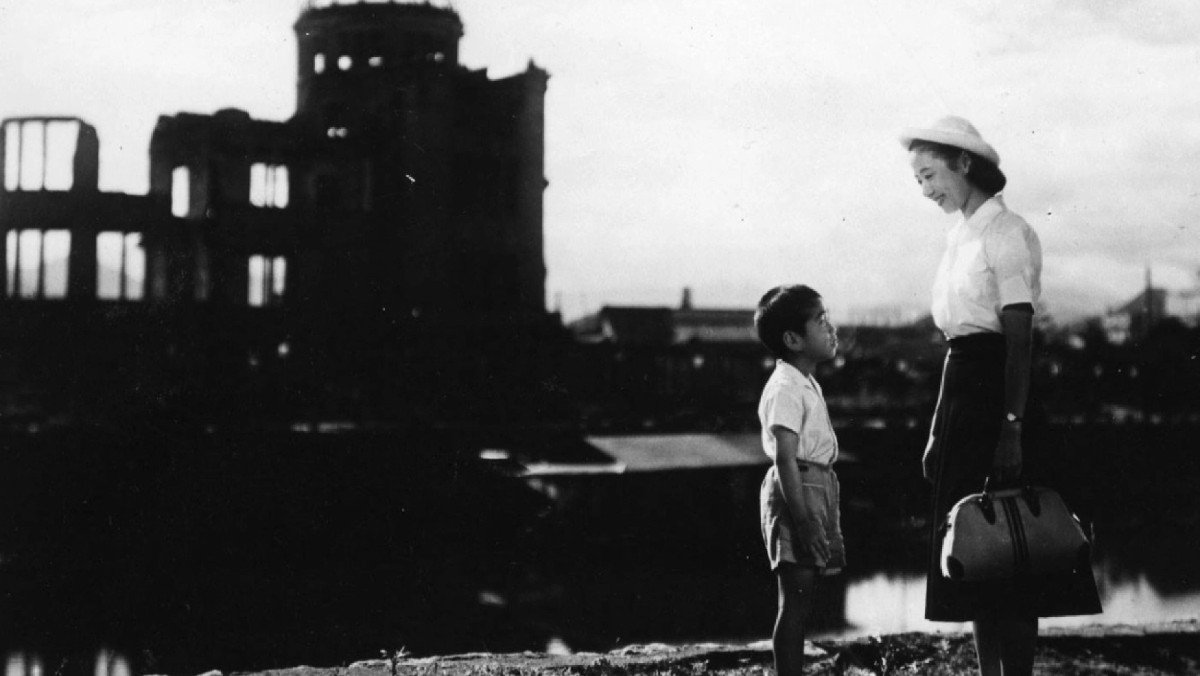 A young boy speaks to a woman in front of the rubble of the city in Children of Hiroshima.