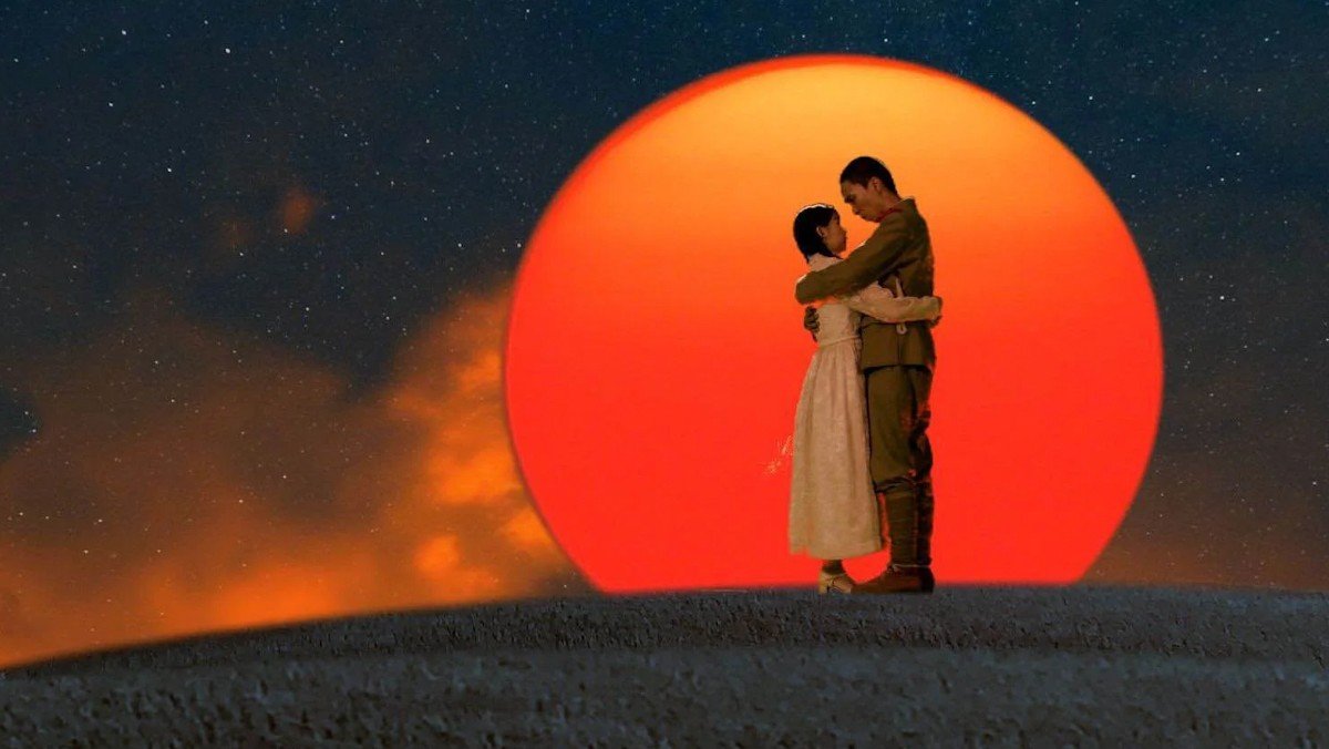 Two lovers embrace in front of a massive, orange sun in Labyrinth of Cinema.