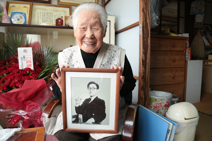 Shitsui Hakoishi holding a photo of her husband